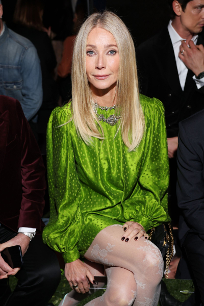 Gwyneth Paltrow poses at a Valentino fashion show in a green dress straight blonde hair and a dark manicure.